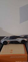 Left side view of silver/black/orange Aston Martin Valkyrie model car on box