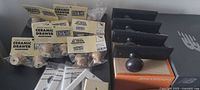 Packaged beige ceramic drawer knobs and screws beside black metal door knobs