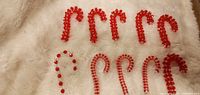 Group shot of all ten red and clear beaded candy cane ornaments on white surface