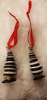 Two handmade button tree ornaments with red ribbons on white surface