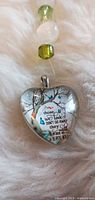 Close view of glass heart pendant with tree graphic and quote