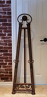 Full view of decorative cast metal easel against wall