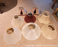 Seven assorted lamp shades arranged on carpet
