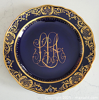 Front of cobalt blue Meissen plate showing gilt monogram and decorative rim