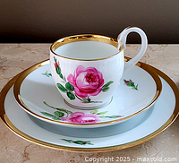 Teacup on saucer and plate showing rose motif and gilt rims