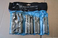 Front view of sealed blue vinyl pouch containing 12 hollow punches with printed size range on black header