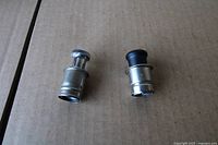Two cigarette lighter inserts side by side on cardboard surface