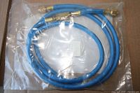 Coiled blue A/C hose with brass ends and valve in sealed plastic bag