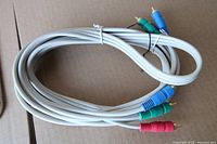 Coiled grey component video cable showing three RCA male connectors (red, green, blue)