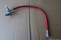 Full view of red A/C recharge hose showing both ends and fittings