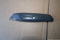 Full view of Millers Falls gray metal utility knife on cardboard surface