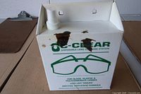 Front view of OC-Clear lens cleaning station showing box graphics and pump dispenser
