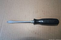 Full view of Snap-on flat screwdriver laying on cardboard