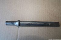 single steel chisel with flat edge and round shank on cardboard surface