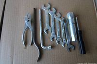 All tools laid out on cardboard: pliers, six wrenches, hex key, pry bar, spark plug socket, screwdriver