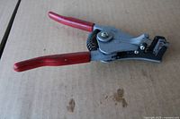 Wire stripper side view showing red handles and stripping head