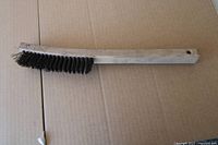 Full view of wooden handle wire brush lying on cardboard background