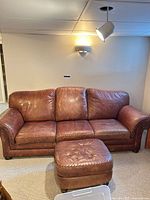 Brown leather three-seat sofa with ottoman front view