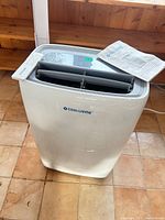 Front and top view of air conditioner with manual on top