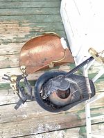 Copper coal scuttle, andirons, shovel and cast iron pot grouped on wooden porch