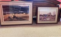 Both framed prints leaning against bed showing size comparison and imagery