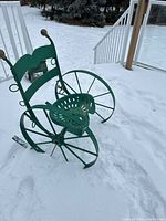 Full view of green metal tractor-seat chair on snow