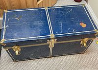 Top view of first blue metal trunk showing brass hardware and surface scratches