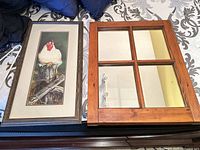 Framed rooster print and 4-pane mirror side by side on bed