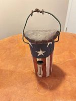 painted wooden birdhouse, cylindrical with star accents and wire handle