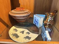 Shelf with southwest jar, buffalo plate, gold pitcher, small book