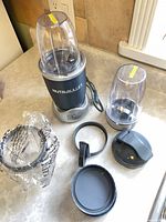 NutriBullet base, two cups, lids, ring, sealing ring visible