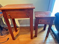 Front view of both wooden side tables showing drawers and overall condition