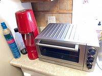 SodaStream unit, bottle, CO2 cylinder and stainless toaster oven on countertop