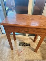 Full view of oak side table showing top surface and brass handle