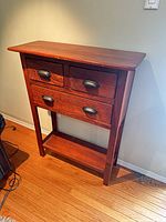 Front view of solid wood console table showing three drawers and lower shelf