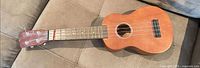 Full view of soprano ukulele on couch showing body, neck, headstock