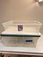 Two clear plastic storage containers, top bin shown without lid stacked on larger bin