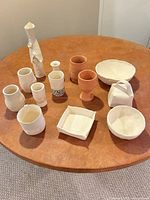 All eleven unglazed ceramic pieces grouped on table