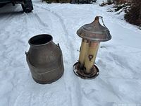 Milk can and hanging bird feeder standing on snow