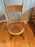 Front view of oak spindle-back rocking chair showing leather seat and spindles