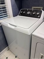 Full view of white GE top-load washer beside dryer