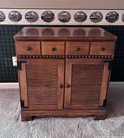 Front view of wood cabinet showing three drawers and two shutter doors