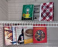 Seven cookbooks on wire shelf