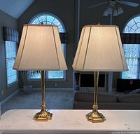 Pair of square column brass lamps on counter, shades visible