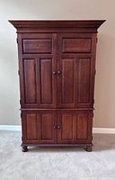 Front view of wood armoire showing overall design and doors
