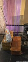 Two sealed cardboard boxes, one rolled curtain, purple beaded curtain hanging