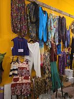 Wall display of handmade garments including pants, vest, dresses and jumpsuit