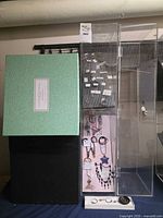 Lot overview showing green box, hoop earring board, tall acrylic cabinet