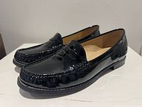 pair of black patent leather loafers angled view