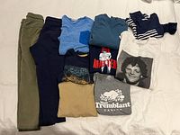 Full lot overview showing all ten clothing pieces folded on bed